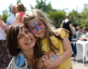 Mother and Face Painted Daughter cuddle at Fair
